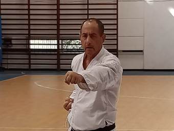 קראטיסט בחגורה שחורה עומד בעמידת קרב עם אגרוף קדימה באולם ספורט במהלך מבחן דרגה